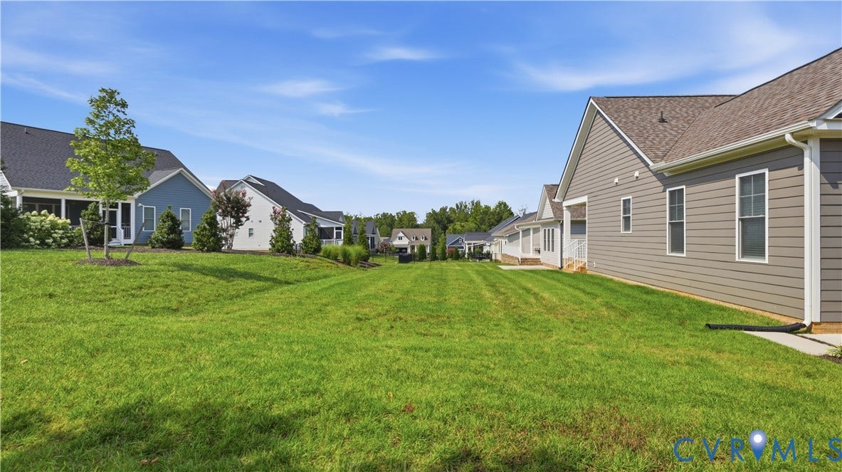 Expansive green space featuring a sloped lawn and mature trees