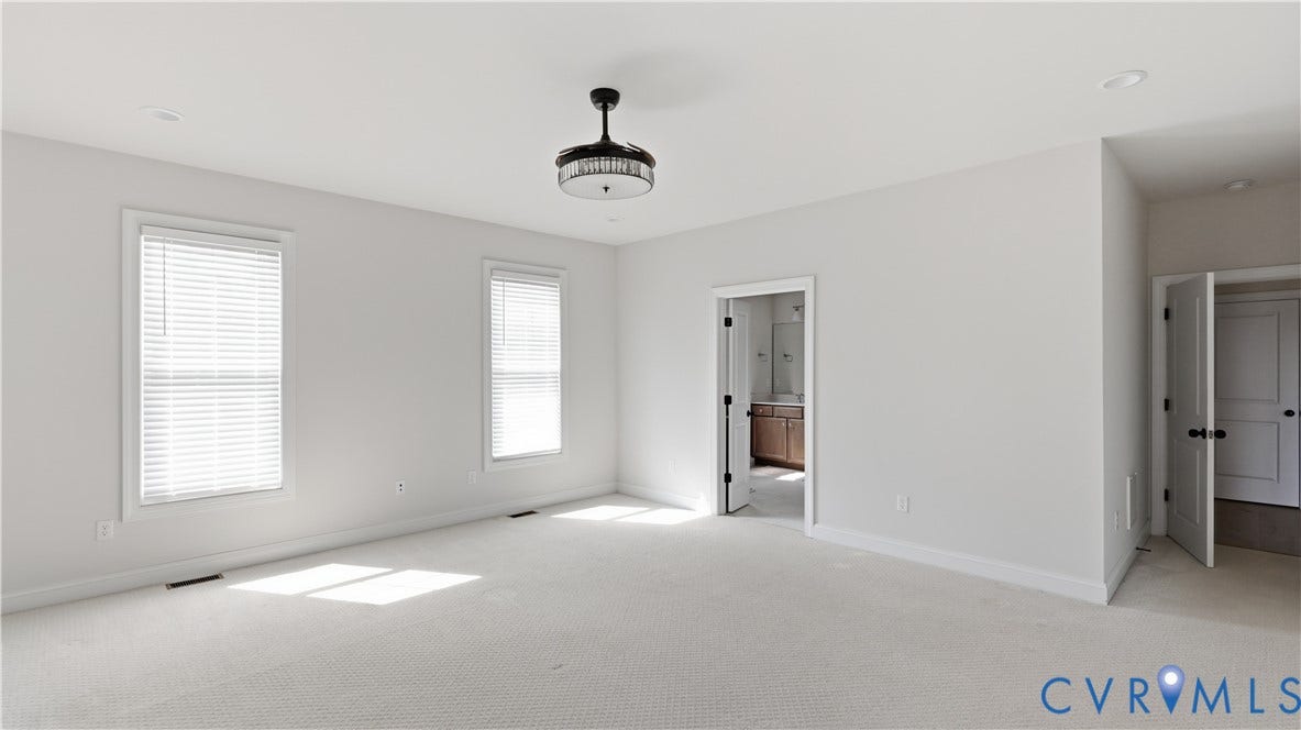 Spacious room featuring light-colored carpeting, multiple windows with blinds, a modern ceiling light fixture, and recessed lighting