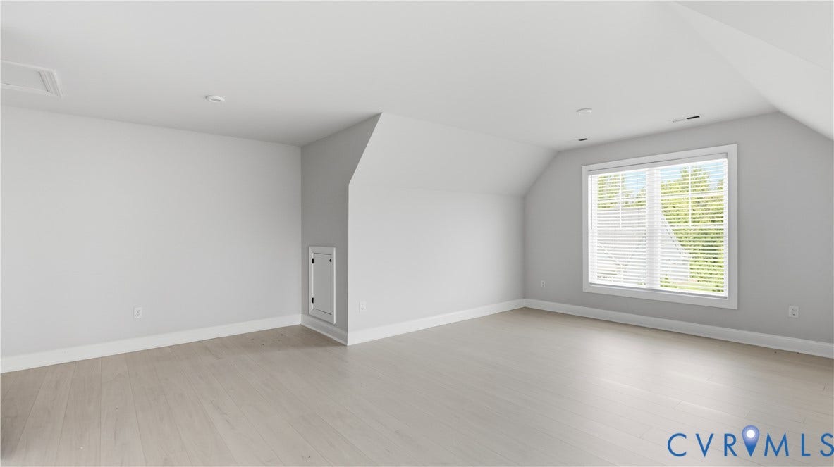 Spacious room with wood-finish flooring, recessed lighting, and a large window with blinds