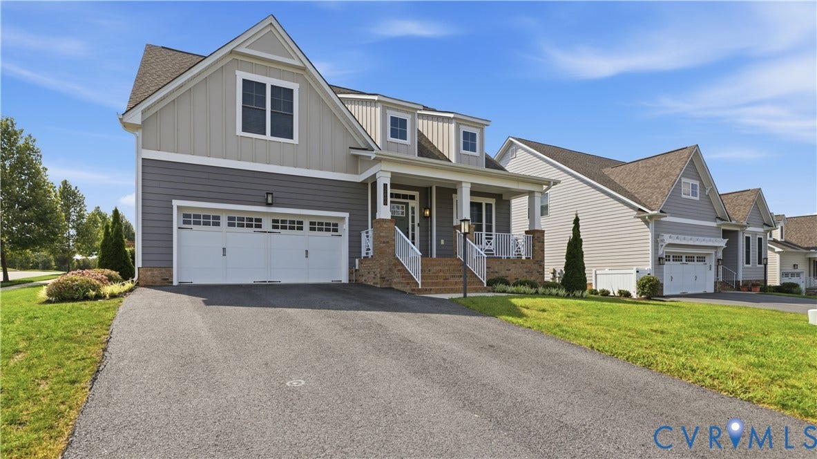 Two-car attached garage, covered front porch, brick foundation accent, and a paved driveway