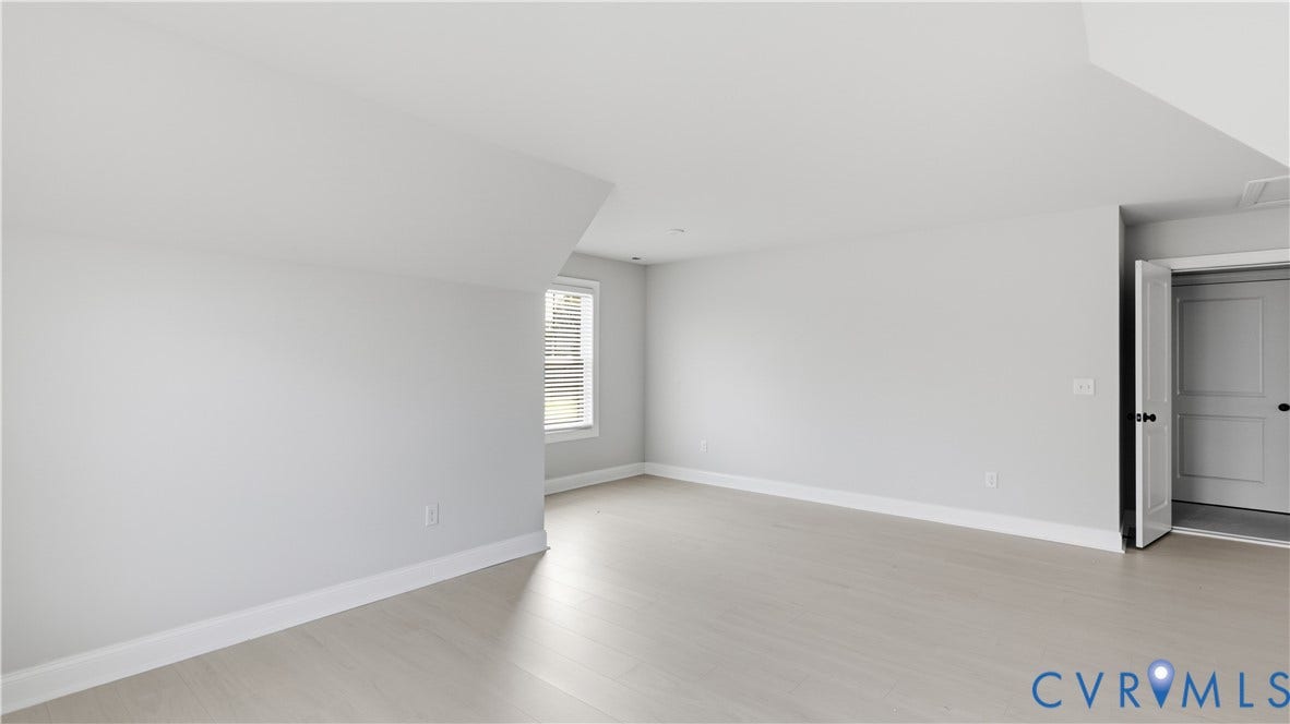 Recessed window with horizontal blinds, light wood-finish flooring, and a white interior door with black hardware