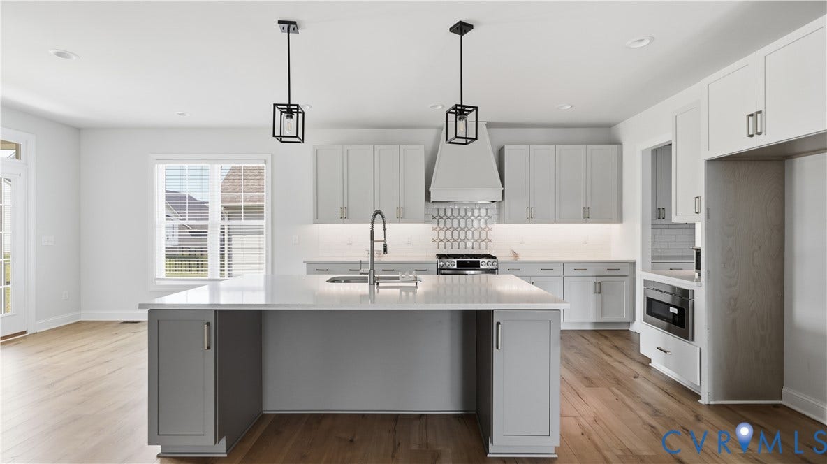 Contemporary kitchen featuring a large center island with gray cabinetry, white quartz countertops, and stainless steel appliances including a gas cooktop and range hood