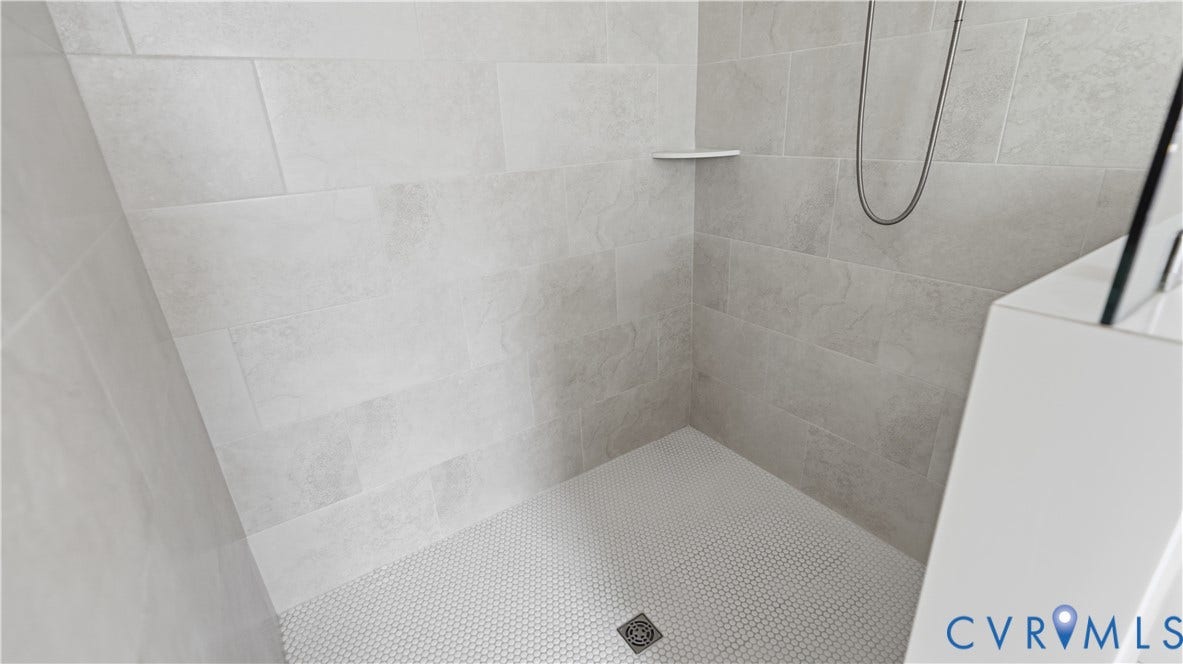 Tiled shower enclosure featuring light-colored rectangular wall tiles and a white penny-round floor