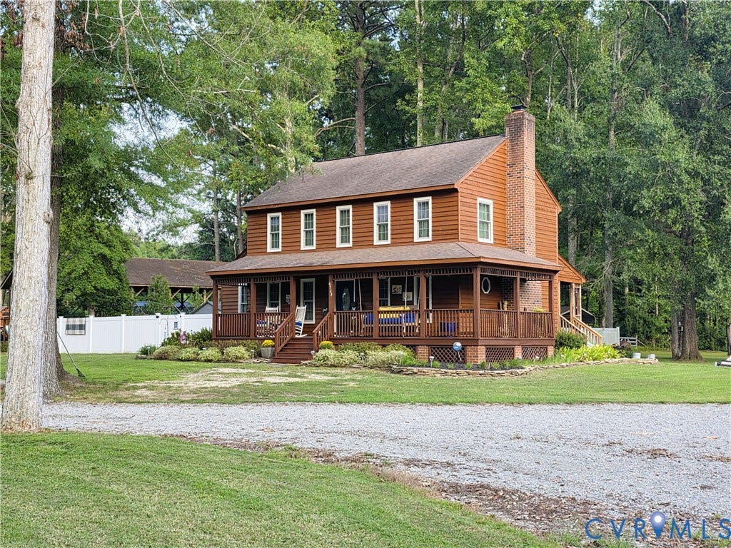 6723 Bull Hill Road, Prince George, VA 23875 Two-story wood-sided exterior with a full-length covered porch, stone-accented chimney, and gravel driveway