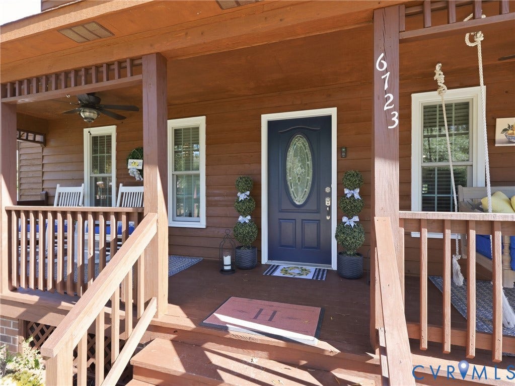 6723 Bull Hill Road, Prince George, VA 23875 Covered wood-plank porch featuring a decorative lattice ceiling border, dark-finished entry door with an oval glass inset, and wood-finish railings