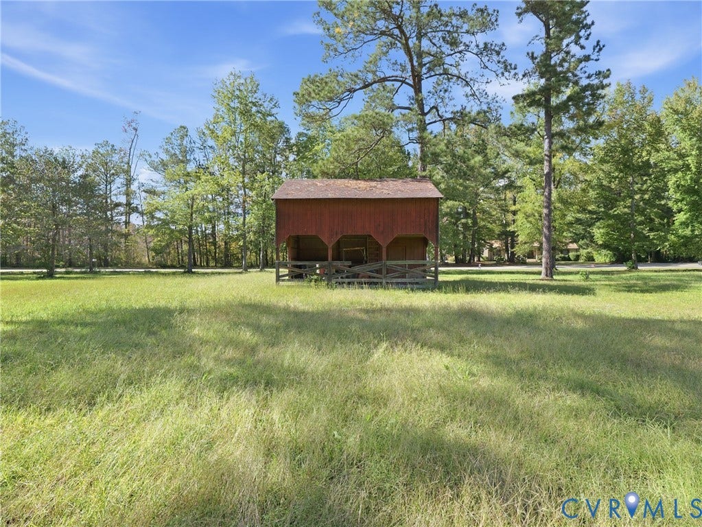 6723 Bull Hill Road, Prince George, VA 23875 Open acreage featuring a rustic wood-sided outbuilding with an attached rail fence and mature perimeter trees