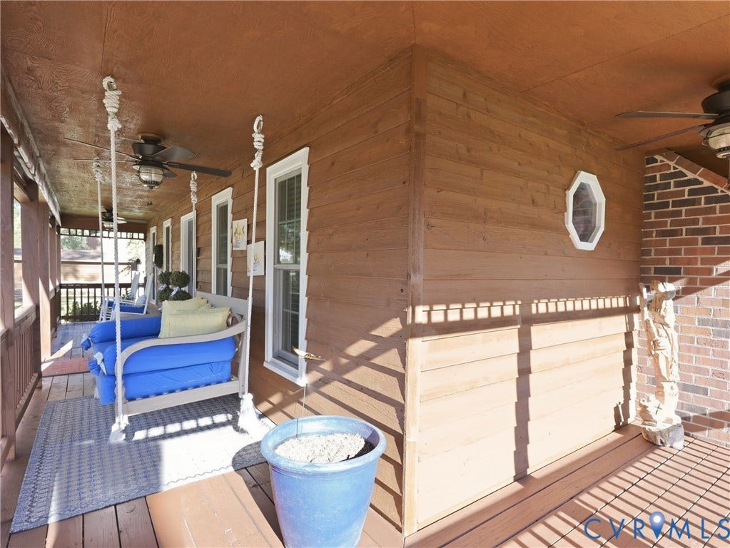 6723 Bull Hill Road, Prince George, VA 23875 Covered porch featuring wood-plank siding, a red brick accent wall, white-trimmed windows, and ceiling-mounted fans