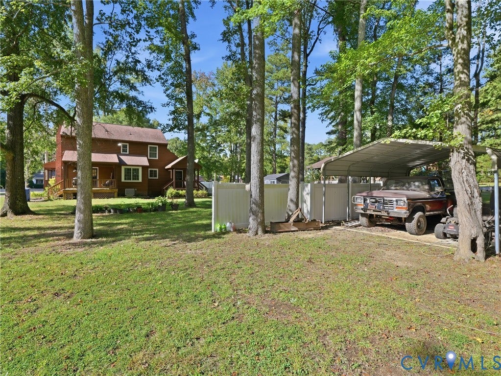 6723 Bull Hill Road, Prince George, VA 23875 Expansive backyard featuring mature trees, white vinyl privacy fencing, and a metal-roofed carport