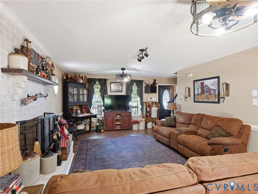 6723 Bull Hill Road, Prince George, VA 23875 Living area featuring a floor-to-ceiling brick fireplace with a custom wood mantel, wood-finish flooring, and drum-style ceiling light fixtures