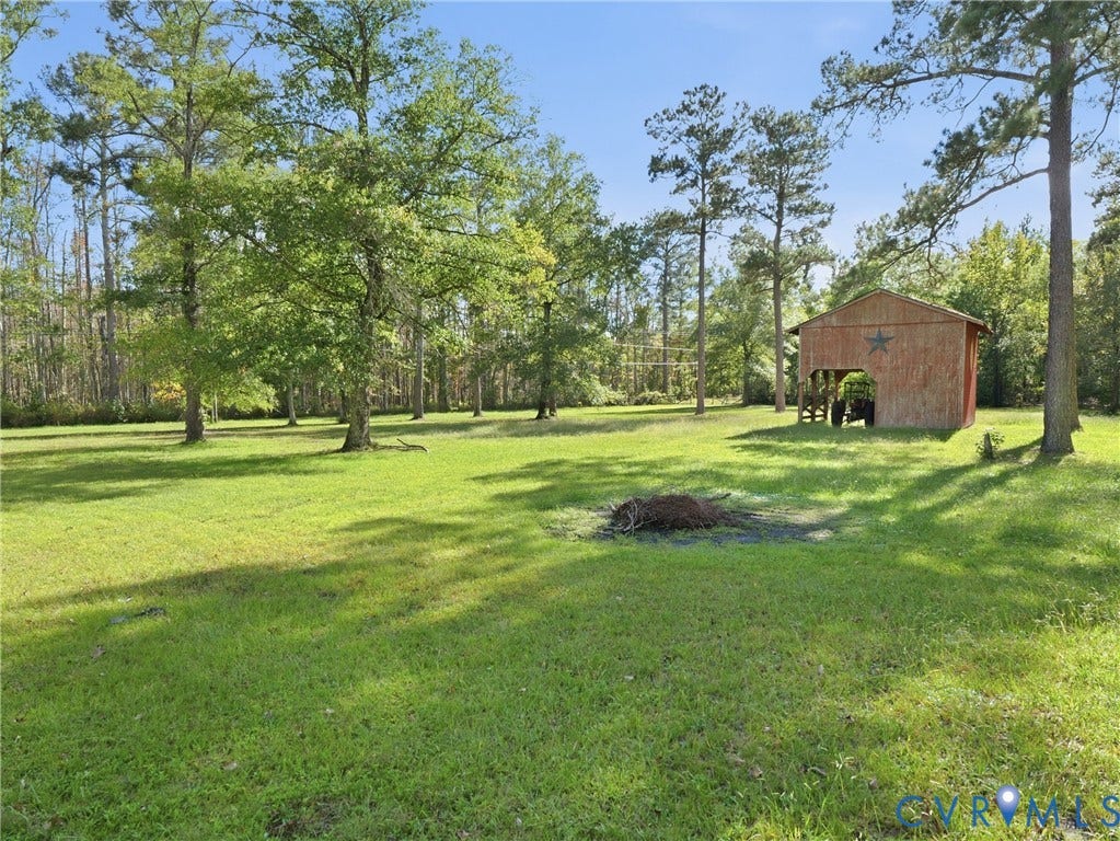 6723 Bull Hill Road, Prince George, VA 23875 Expansive grounds featuring mature shade trees, open grassy areas, and a detached wood-frame structure with an integrated covered storage bay