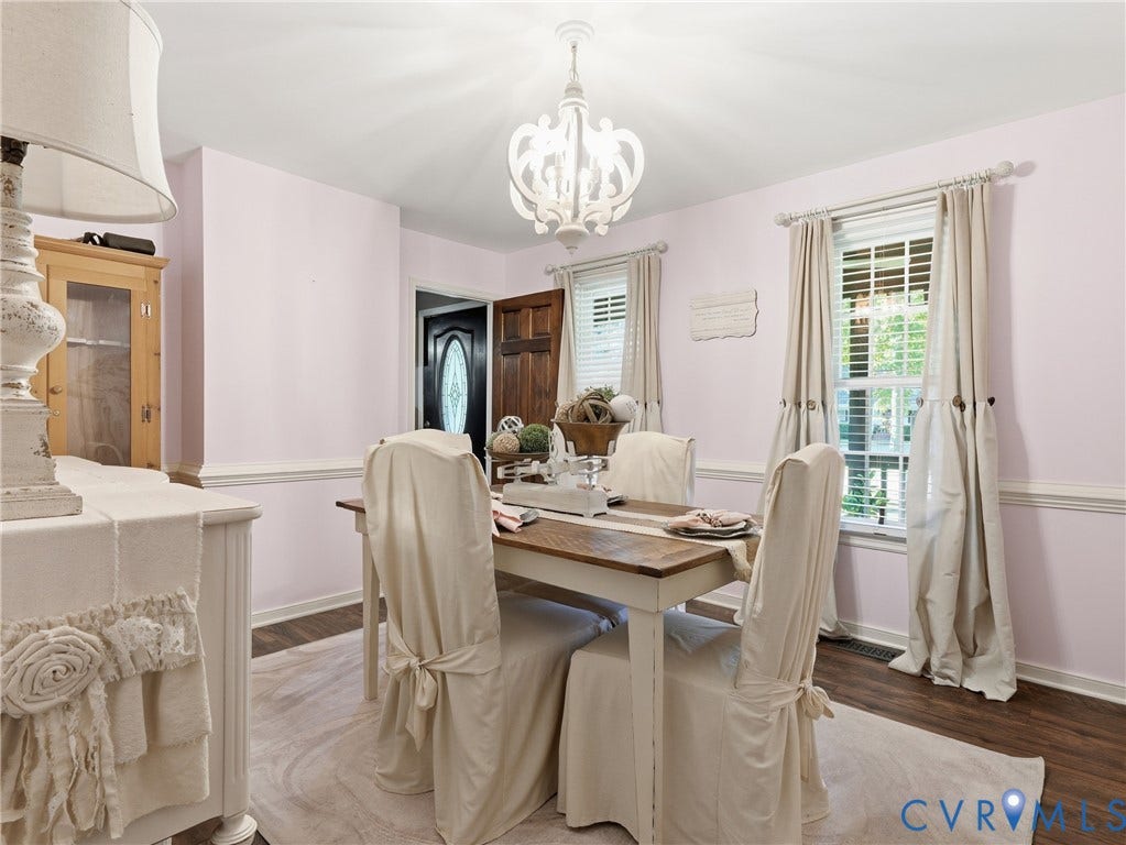 6723 Bull Hill Road, Prince George, VA 23875 Dining space featuring wood-finish flooring, decorative chair rail molding, a white multi-arm chandelier, and a wood-paneled door with an oval glass insert