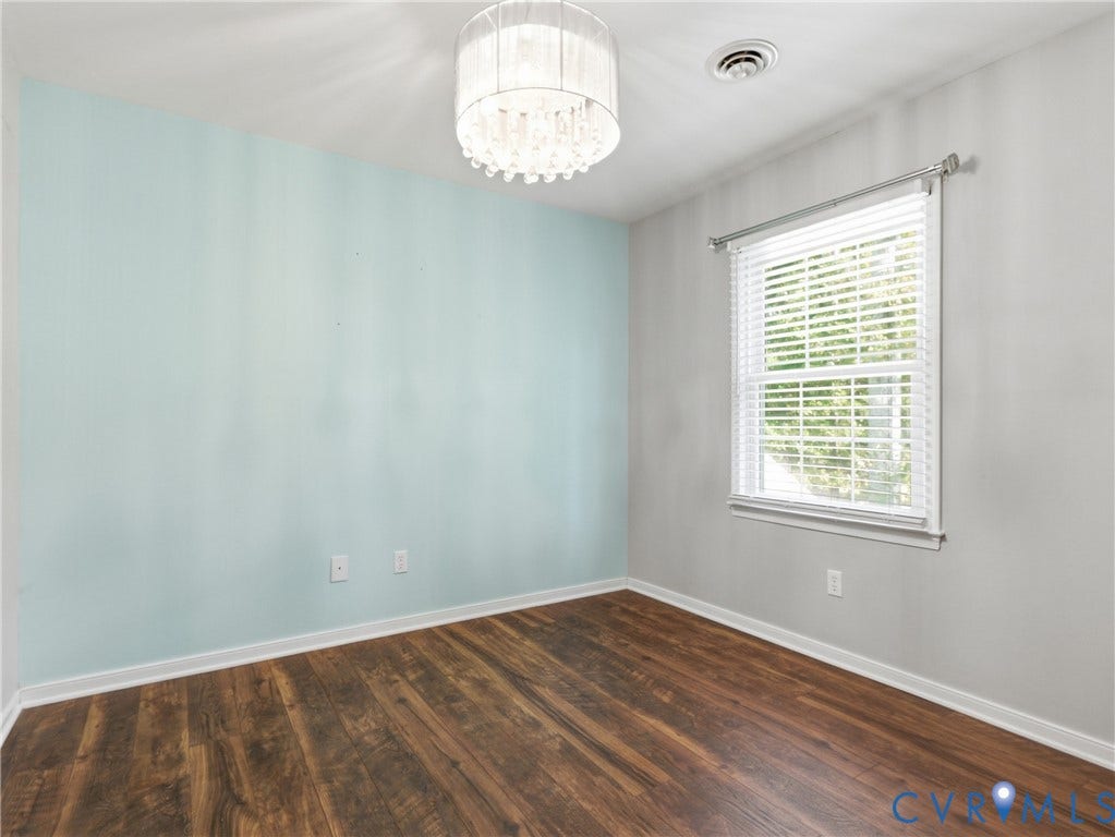 6723 Bull Hill Road, Prince George, VA 23875 Wood-finish flooring, accent wall, and tiered crystal drum chandelier with an attached window featuring horizontal blinds