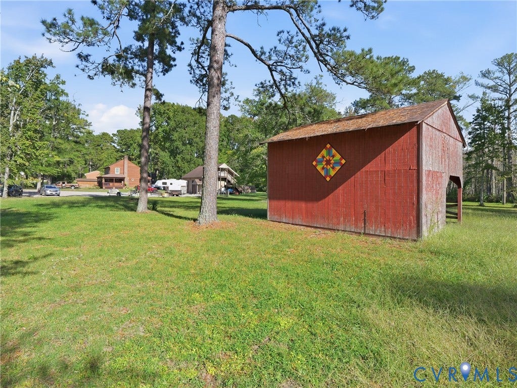 6723 Bull Hill Road, Prince George, VA 23875 Rustic barn featuring board-and-batten siding, a gable roof, and mature trees on an expansive, open lot