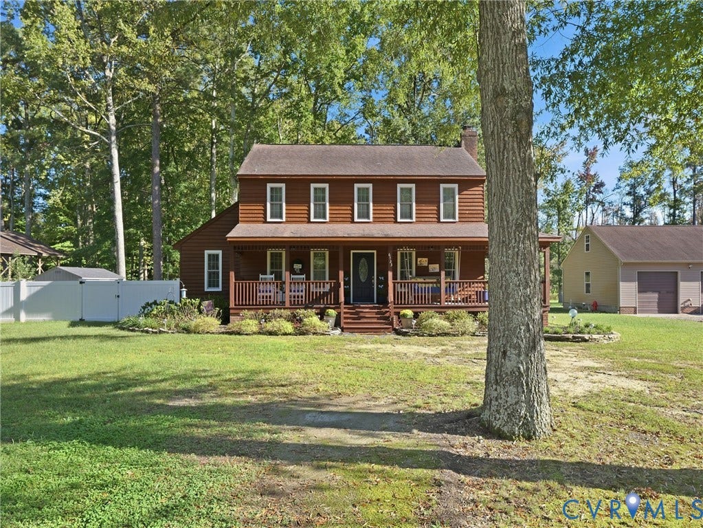 6723 Bull Hill Road, Prince George, VA 23875 Two-story wood siding exterior featuring a covered front porch, stone-bordered landscaping, and a detached garage