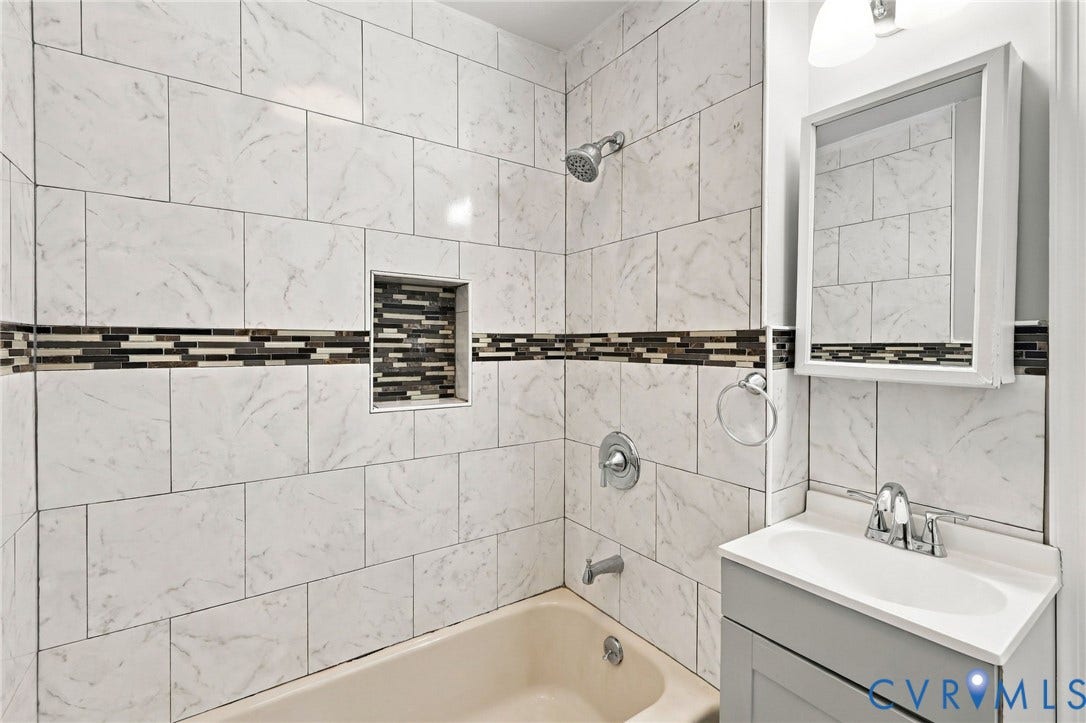 1432 Ferndale Avenue, Petersburg, VA 23803 Bathtub with white subway tile surround, decorative mosaic tile accent band, built-in shower niche, and a chrome shower head with coordinating fixtures