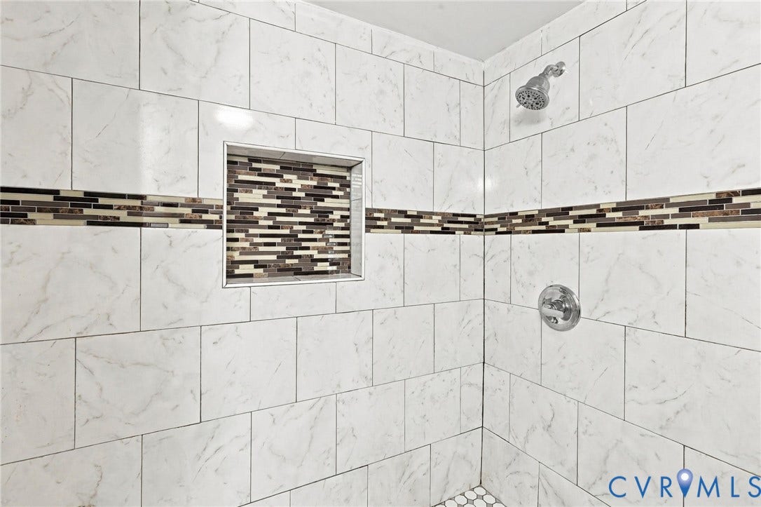 1432 Ferndale Avenue, Petersburg, VA 23803 Tiled shower with white rectangular tiles, a decorative mosaic tile band, a recessed niche, and a chrome shower head and controls