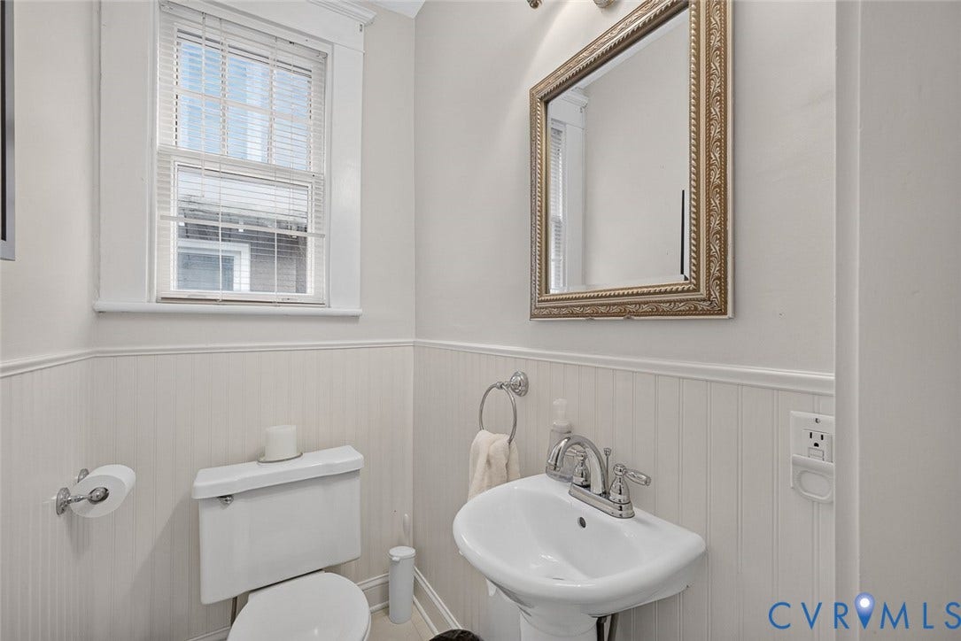 3812 Fauquier Avenue, Bellevue, Richmond, VA 23227 White pedestal sink with chrome faucet, a decorative framed mirror, and beadboard wainscoting