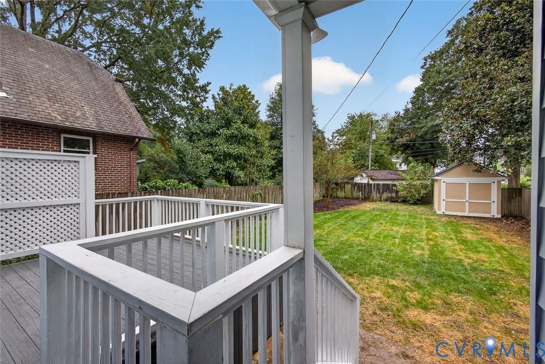 3812 Fauquier Avenue, Bellevue, Richmond, VA 23227 Exterior wood-finish deck with lattice privacy panel, wood railing, green lawn, wood fence, and a detached shed