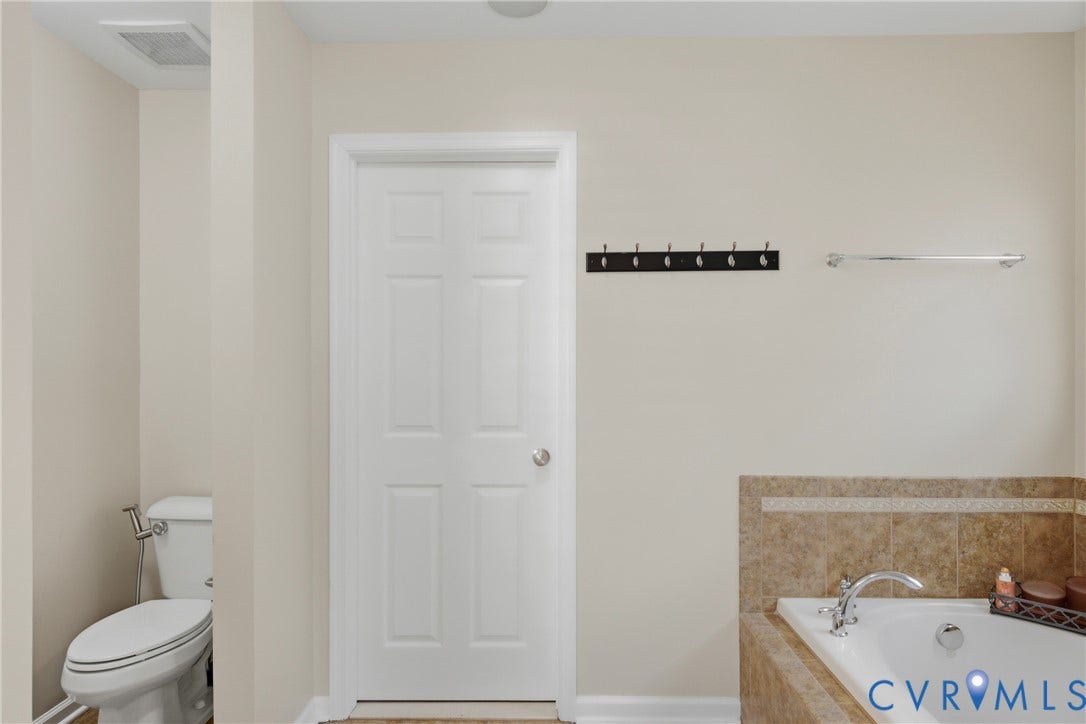 3536 Hunton Ridge Drive, Glen Allen, VA 23059 Built-in soaking tub with tile surround, white paneled door, and a wall-mounted towel bar