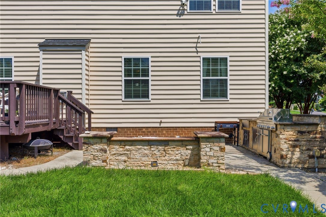 3536 Hunton Ridge Drive, Glen Allen, VA 23059 Exterior featuring horizontal siding, a stained wood deck, an outdoor kitchen with integrated appliances, and a stone-clad retaining wall