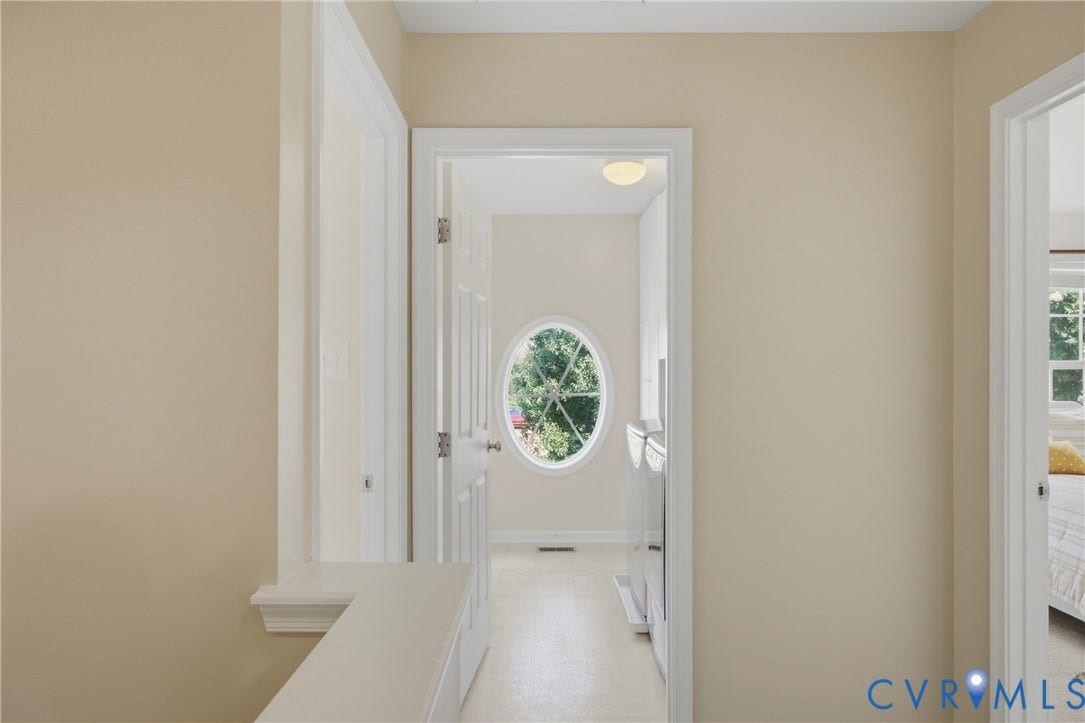 3536 Hunton Ridge Drive, Glen Allen, VA 23059 Hallway with neutral wall tones and white trim, featuring an oval window, two panel doors, and a ceiling-mounted light fixture
