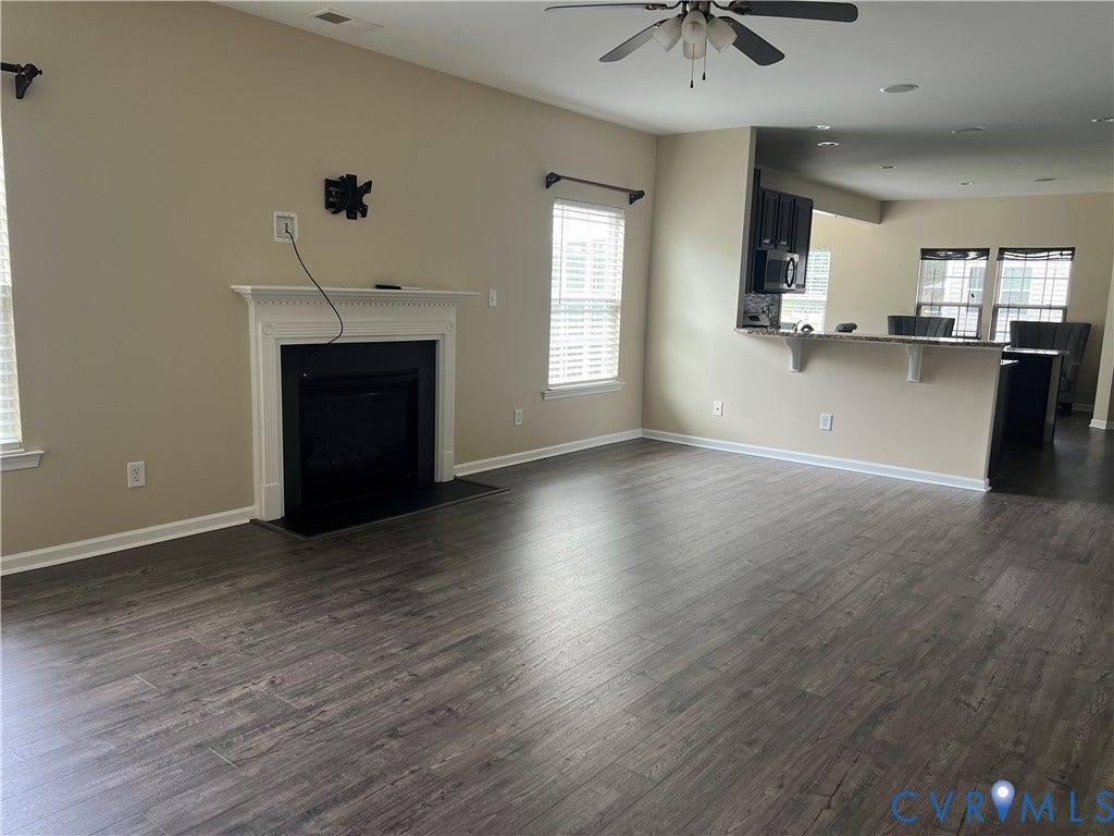 3536 Hunton Ridge Drive, Glen Allen, VA 23059 Living area featuring wood-finish flooring, a fireplace with a white mantel, a ceiling fan, and a breakfast bar with a granite-style countertop