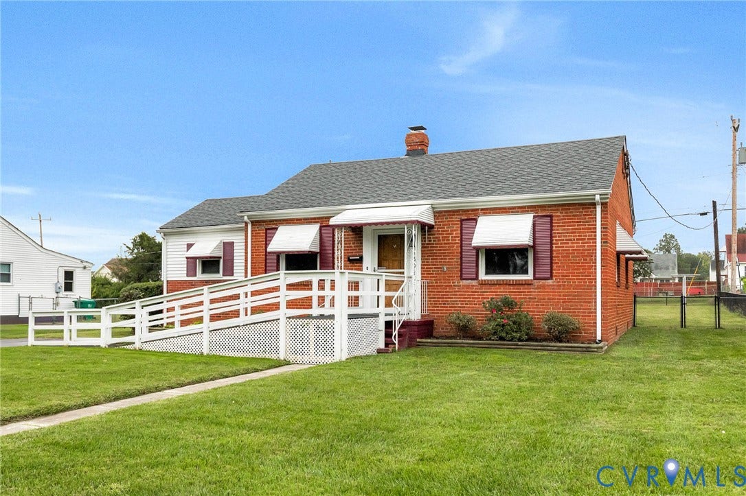 2503 Carlisle Avenue, Henrico, VA 23231 Charming brick ranch home featuring a covered front porch with white railings, multiple large windows with white trim, a pitched roof with gray shingles, and a chimney