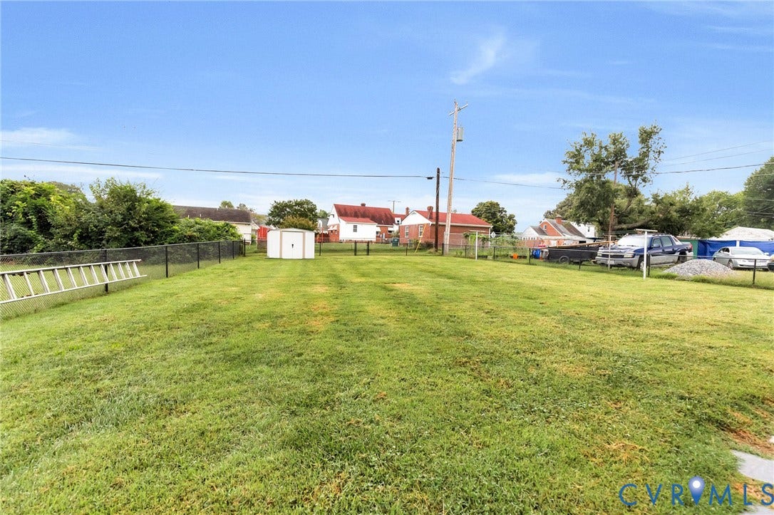 2503 Carlisle Avenue, Henrico, VA 23231 Expansive grassy yard with a black chain-link fence and a white storage shed