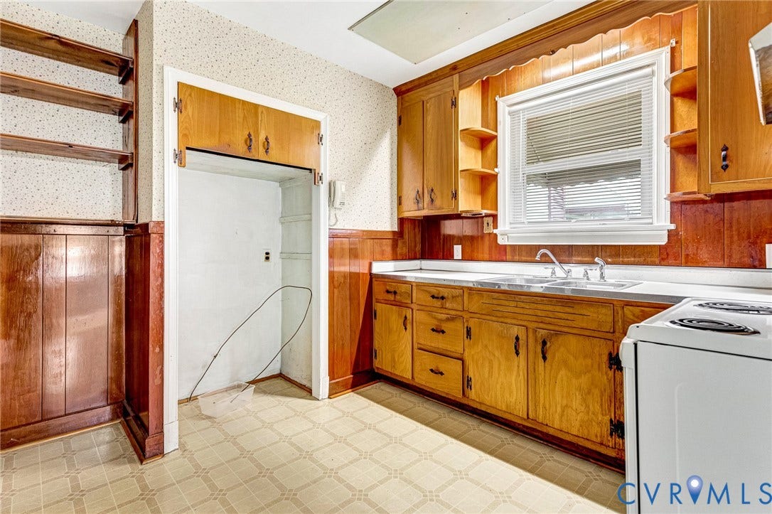 2503 Carlisle Avenue, Henrico, VA 23231 Wood-paneled kitchen featuring extensive cabinetry, built-in shelving, a stainless steel sink, and a white freestanding range