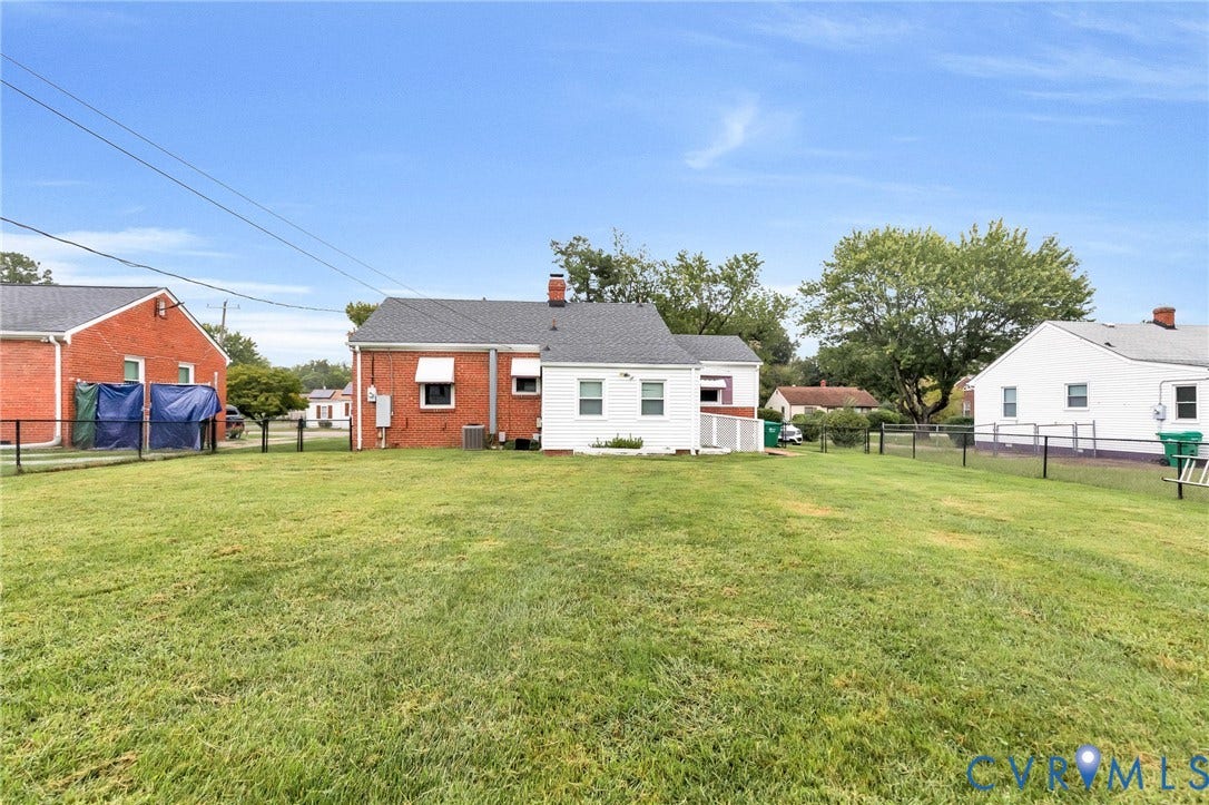 2503 Carlisle Avenue, Henrico, VA 23231 Expansive grassy yard area with a black metal fence, and a white exterior home with a dark shingle roof