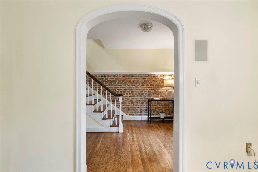 2714 E Broad Street, Church Hill, Richmond, VA 23223 Archway entry leading to a room with exposed brick wall, hardwood flooring, and a staircase with white risers and dark wood treads