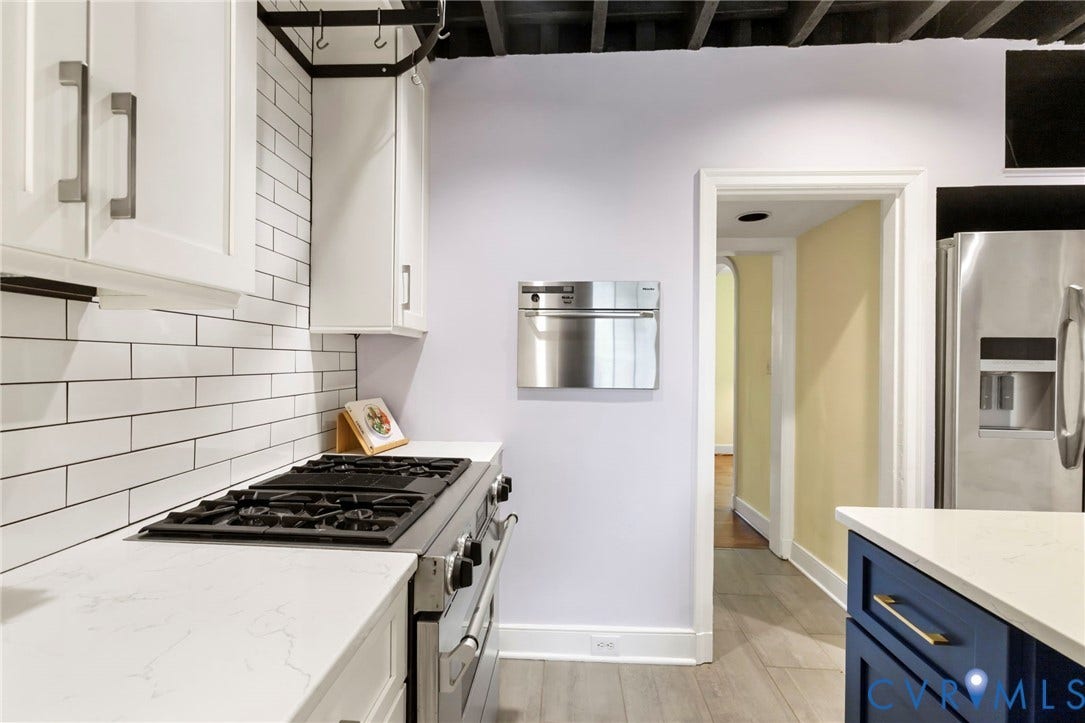 2714 E Broad Street, Church Hill, Richmond, VA 23223 Stainless steel refrigerator, built-in microwave, gas range, wood-finish flooring, and white subway tile backsplash