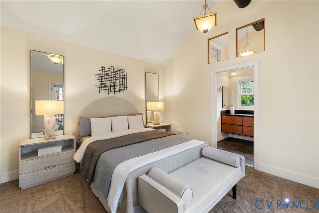 2714 E Broad Street, Church Hill, Richmond, VA 23223 Vaulted ceiling with an attached lighting fixture, plush carpet flooring, and an adjoining bathroom featuring a dark vanity with a light countertop