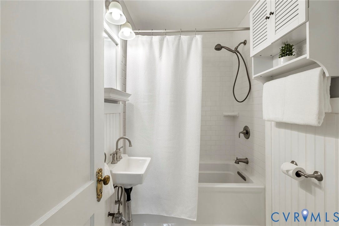 2714 E Broad Street, Church Hill, Richmond, VA 23223 White subway tile shower surround with a built-in tub, pedestal sink with brushed nickel hardware, and beadboard wall paneling