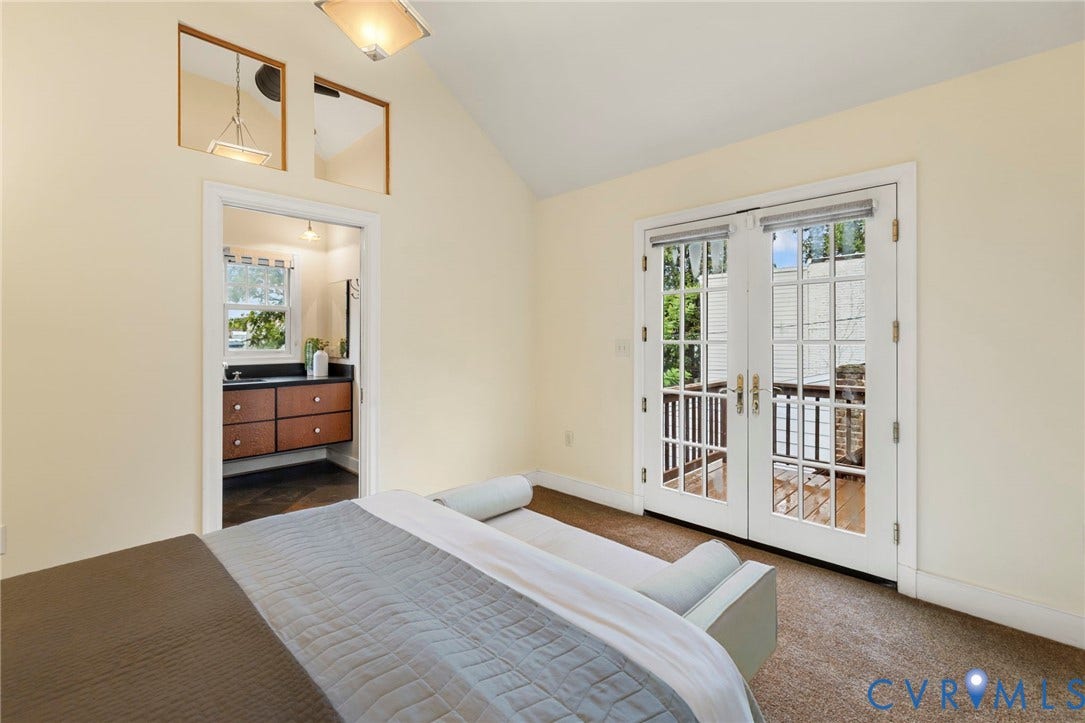 2714 E Broad Street, Church Hill, Richmond, VA 23223 Vaulted ceiling with a flush-mount light fixture, a doorway leading to a bathroom with a floating vanity, and French doors opening to a balcony