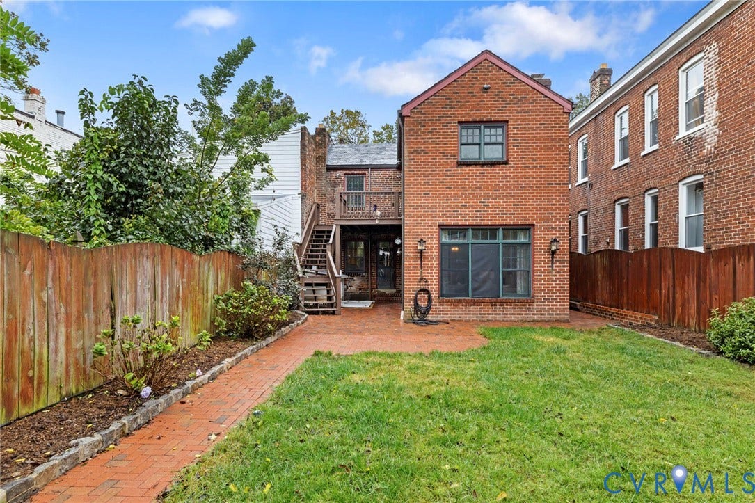 2714 E Broad Street, Church Hill, Richmond, VA 23223 Brick exterior with a second-story wooden balcony, a ground-level brick patio, and a grassy yard