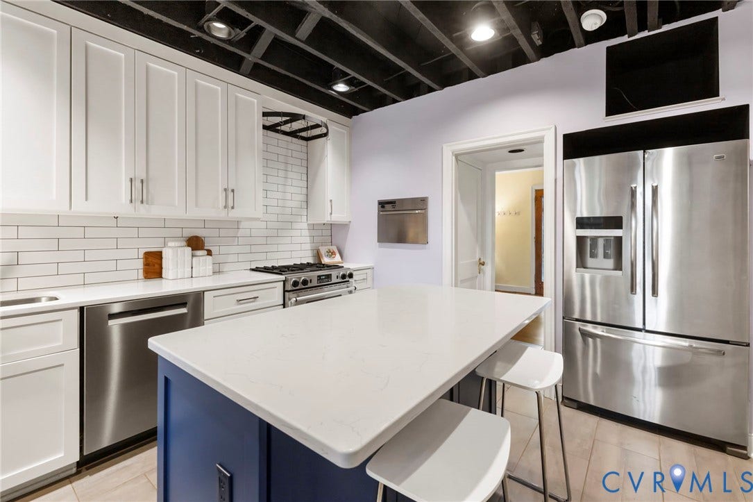 2714 E Broad Street, Church Hill, Richmond, VA 23223 White shaker cabinetry, subway tile backsplash, stainless steel appliances, blue island with white countertop, and light-toned flooring
