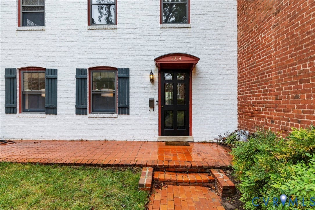 2714 E Broad Street, Church Hill, Richmond, VA 23223 Brick exterior with white painted finish, black paneled door with transom window, brick pathway, and black louvered shutters