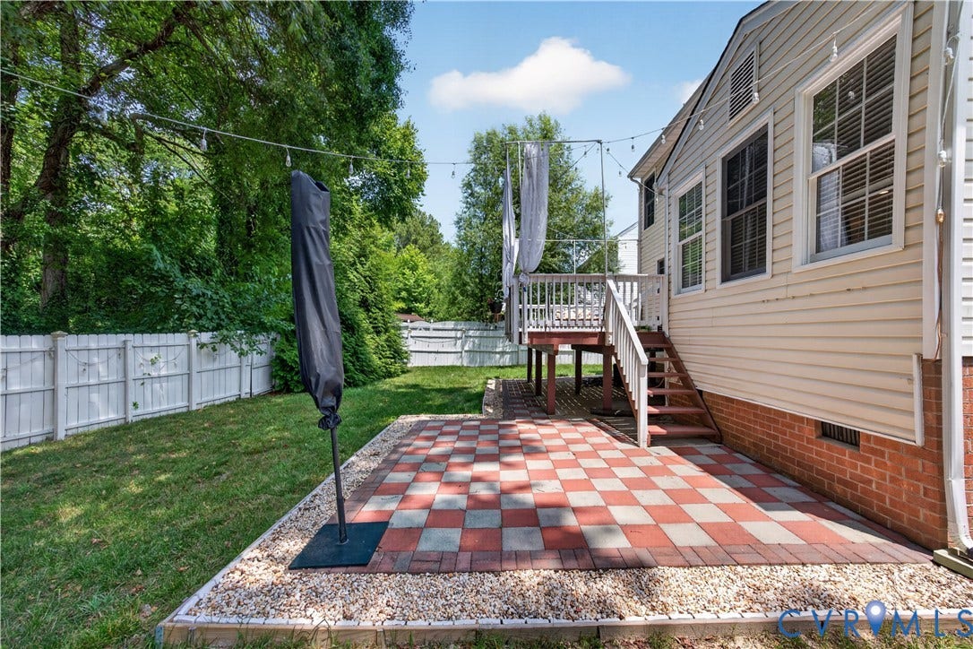 9516 Hungary Woods Drive, Henrico, VA 23060 Expansive backyard featuring a checkered paver patio, a raised wood deck, and a full-height privacy fence