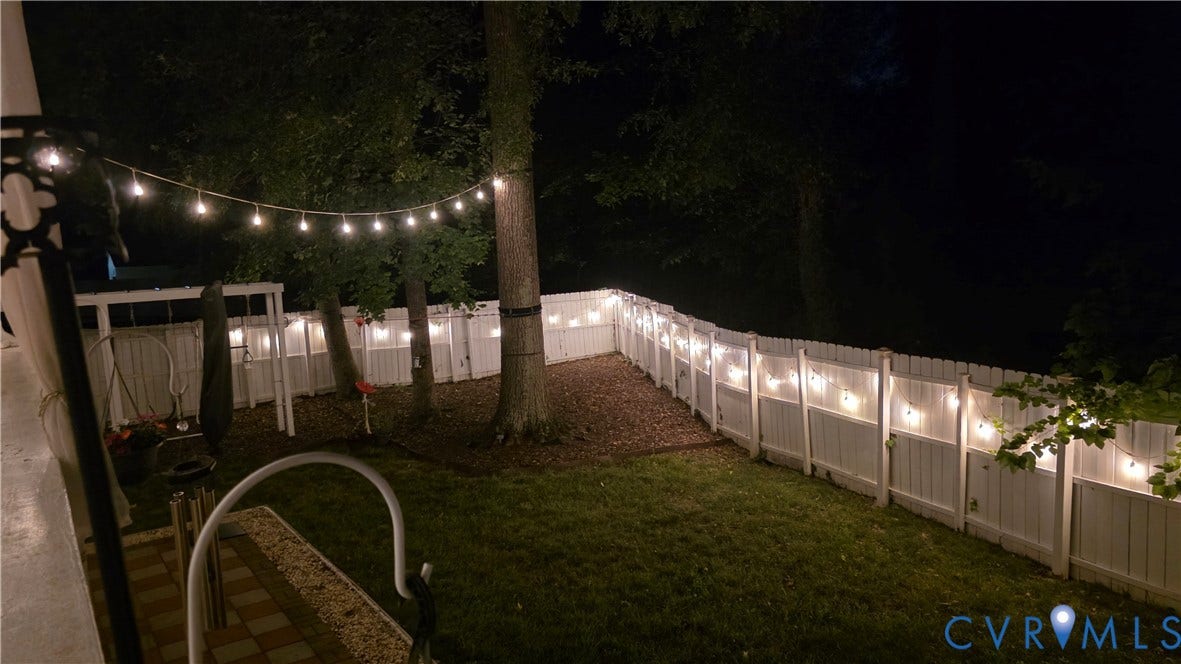 9516 Hungary Woods Drive, Henrico, VA 23060 Fenced backyard featuring string lighting, mature trees, and a patterned patio
