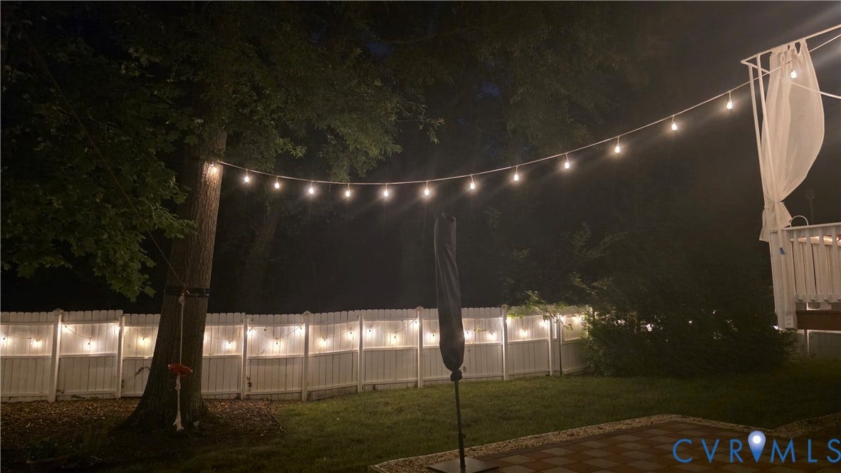 9516 Hungary Woods Drive, Henrico, VA 23060 Expansive backyard featuring a manicured lawn, string lighting, and a white picket fence