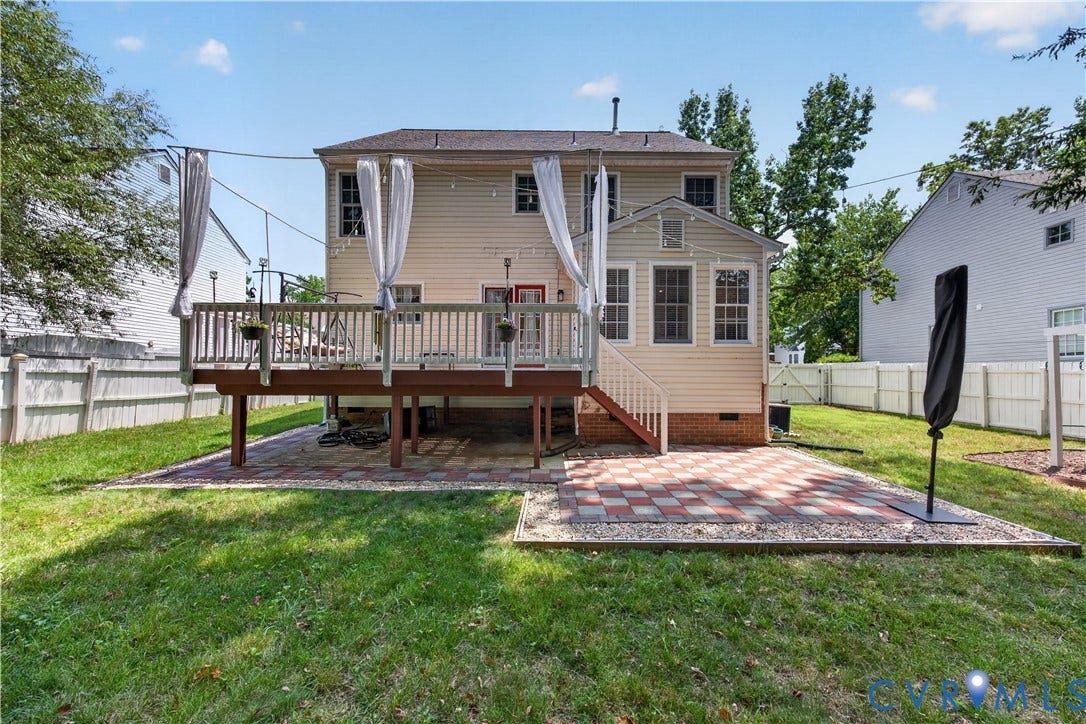9516 Hungary Woods Drive, Henrico, VA 23060 Two-story exterior with a raised wooden deck, a lower patio featuring a checkerboard paver design, and a white privacy fence