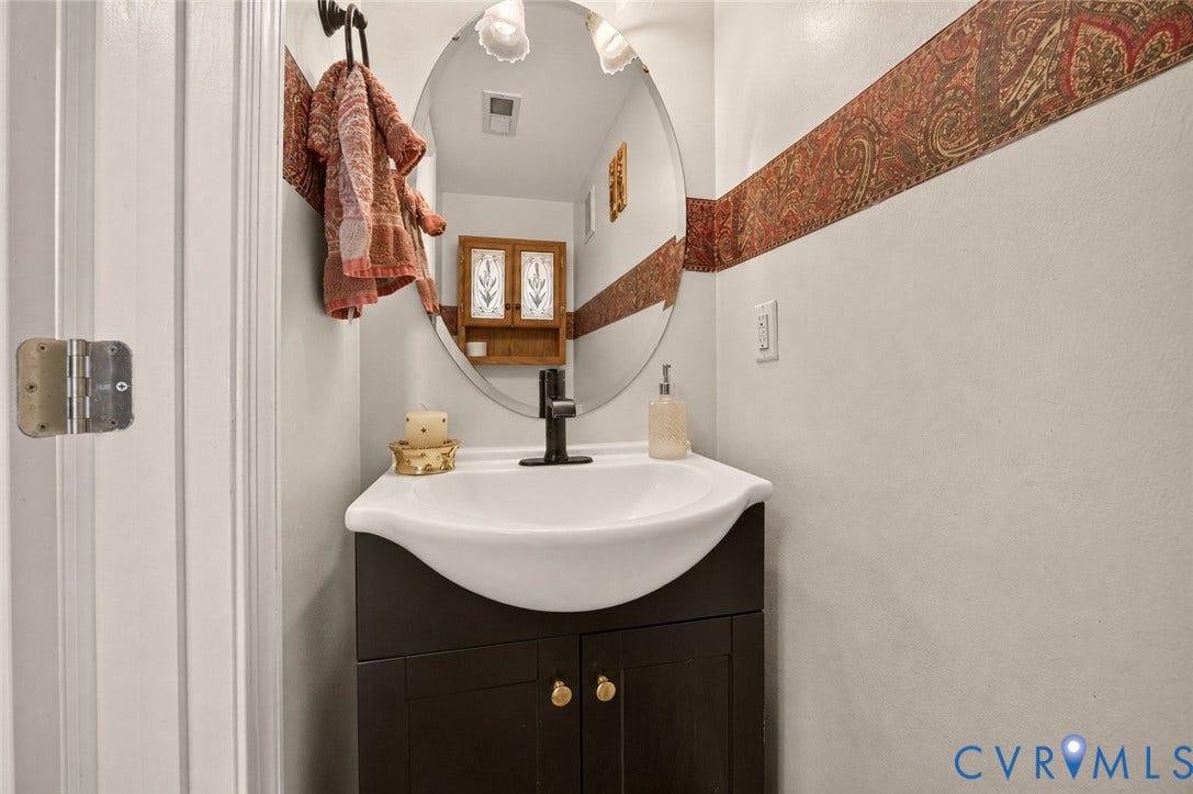 9516 Hungary Woods Drive, Henrico, VA 23060 Powder room with Vanity and an integrated sink and a matte black faucet, complemented by an oval wall-mounted mirror