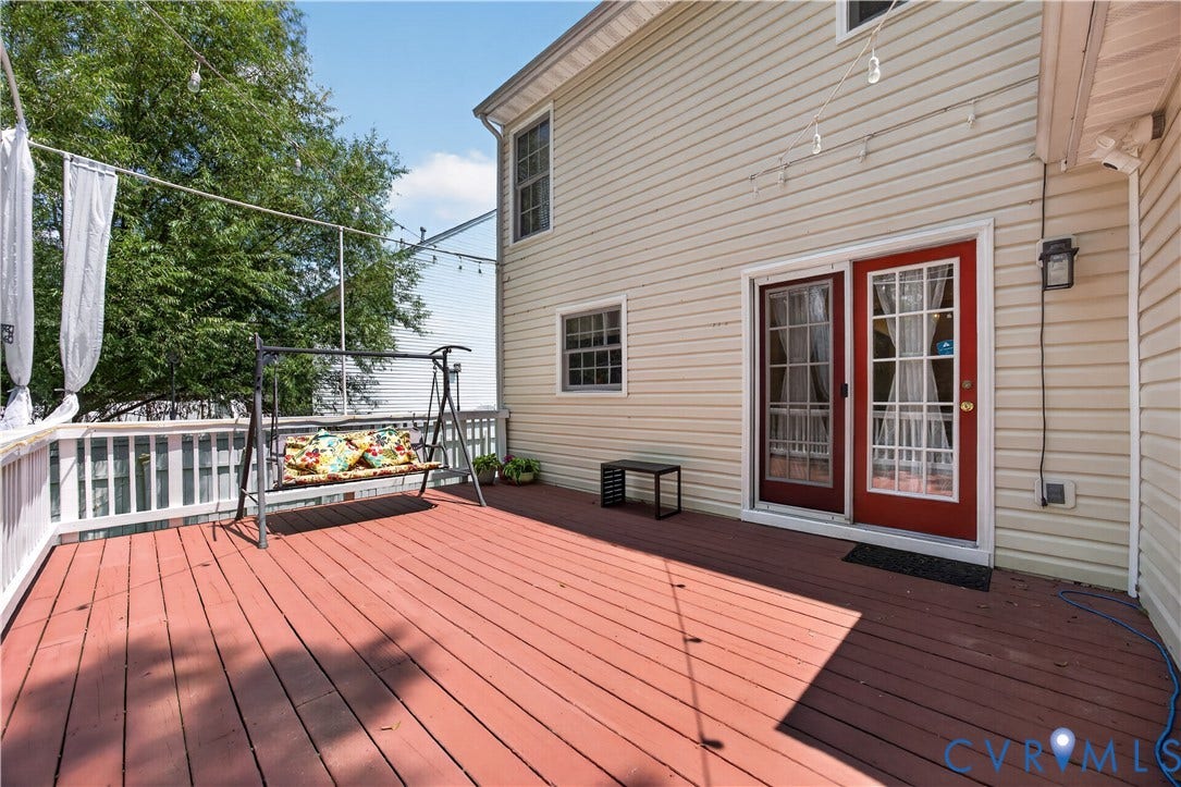 9516 Hungary Woods Drive, Henrico, VA 23060 Expansive wood-finish deck with a white railing, featuring durable siding and a red exterior door with spanish lights