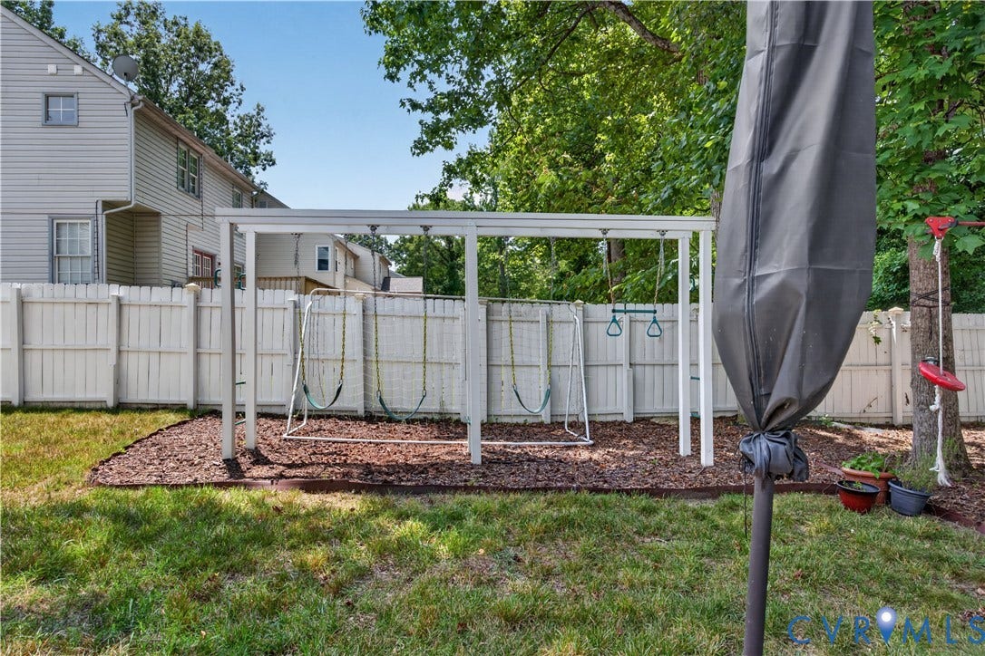 9516 Hungary Woods Drive, Henrico, VA 23060 Fenced backyard featuring a swing set with multiple swings, Zip line, mature trees, and a mulched play area