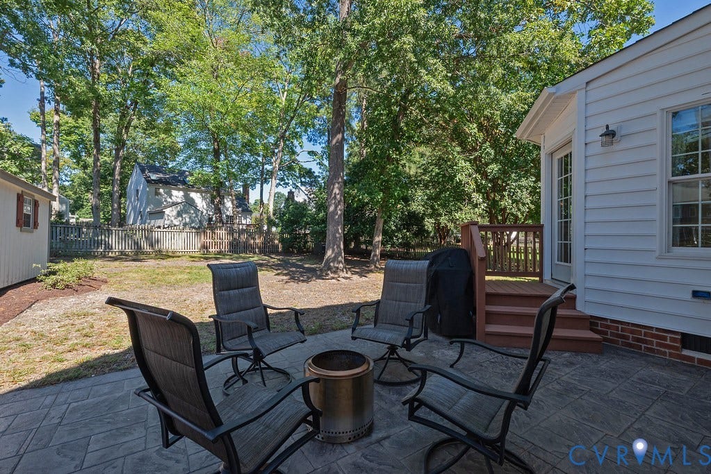 Expansive backyard featuring a stamped concrete patio, stairs to family room, mature trees, and a storage shed