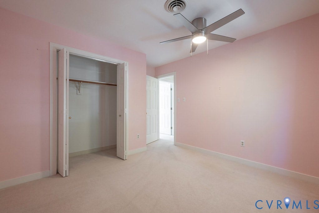 Ceiling fan with integrated lighting, double bifold closet doors, closet hanging rod, and light carpet