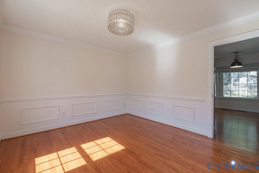 Hardwood flooring, crown molding, chair rail with panel molding, as well as a drum semi-flush mount light fixture