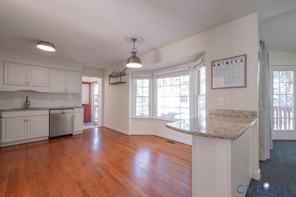 Kitchen featuring white cabinetry, subway tile backsplash, stainless steel dishwasher, and hardwood flooring