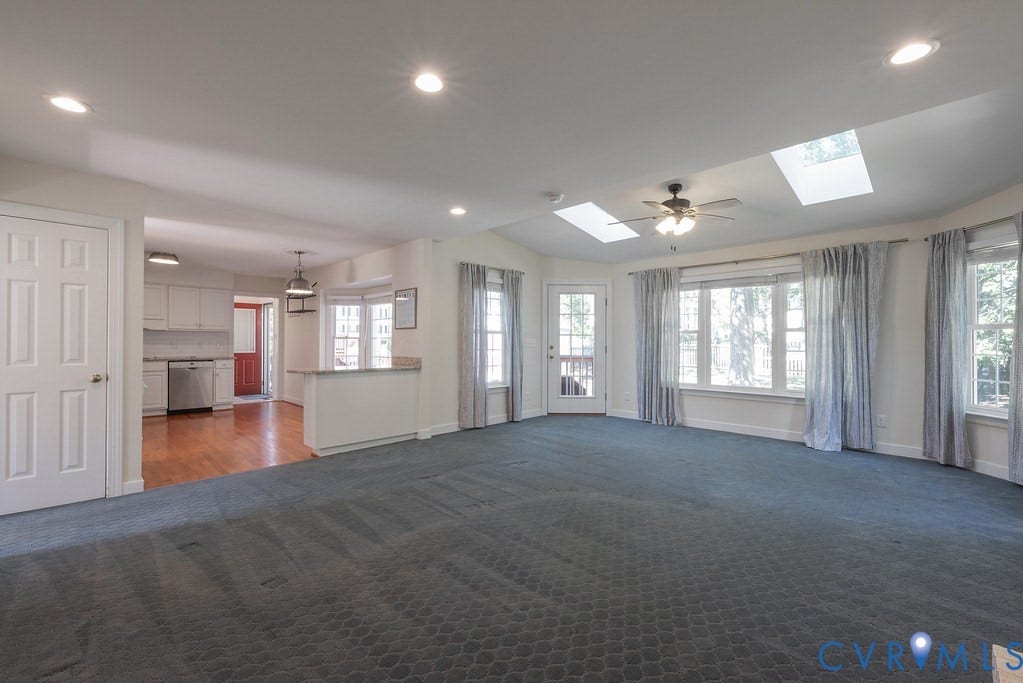 Oversized Living area with vaulted ceiling, recessed lighting, and two skylights